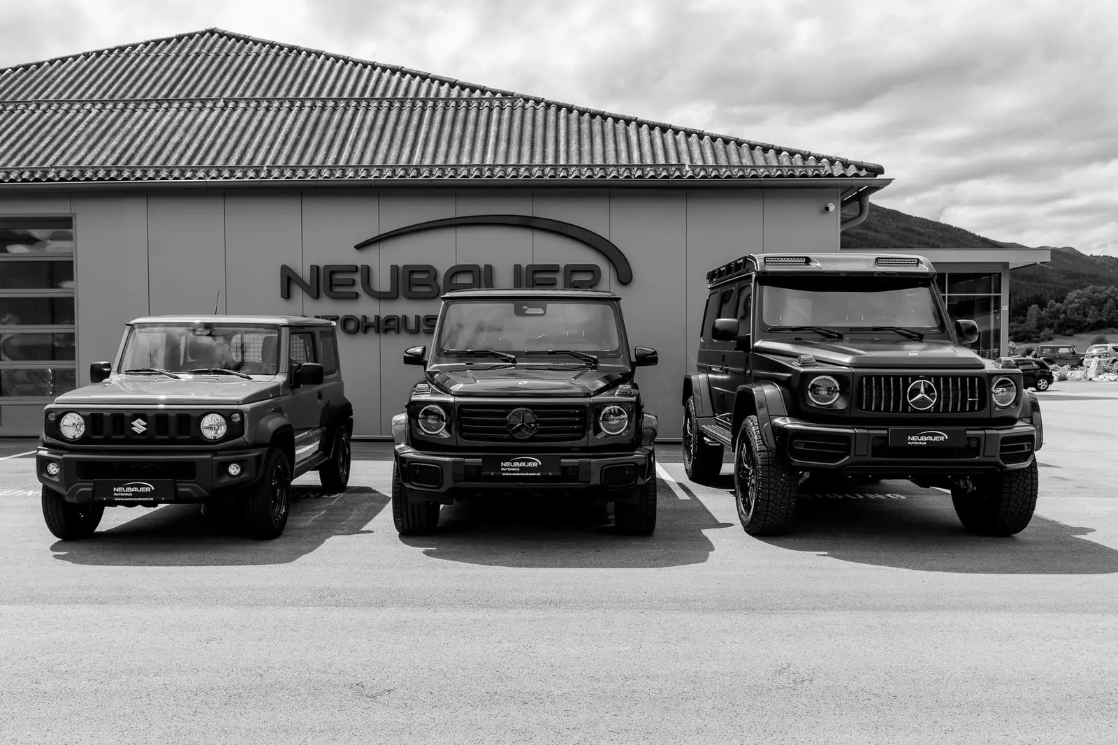 Drei Geländewagen vor dem Autohaus Neubauer in St. Michael im Lungau, Schwarzweißaufnahme