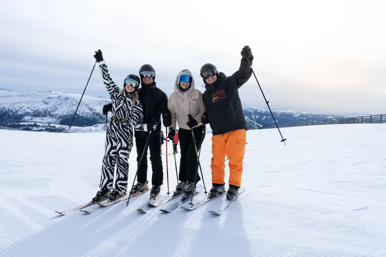 Vier Skifahrer jubeln beim Familien-Skiurlaub auf der Piste am Katschberg