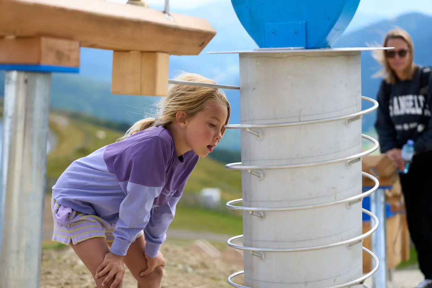 Mädchen beobachtet eine Holzkugel in der Spirale der Kugelbahn am Almspielplatz Aineck