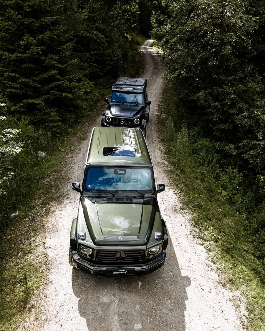 Zwei Geländewagen auf einem Waldweg, von oben fotografiert