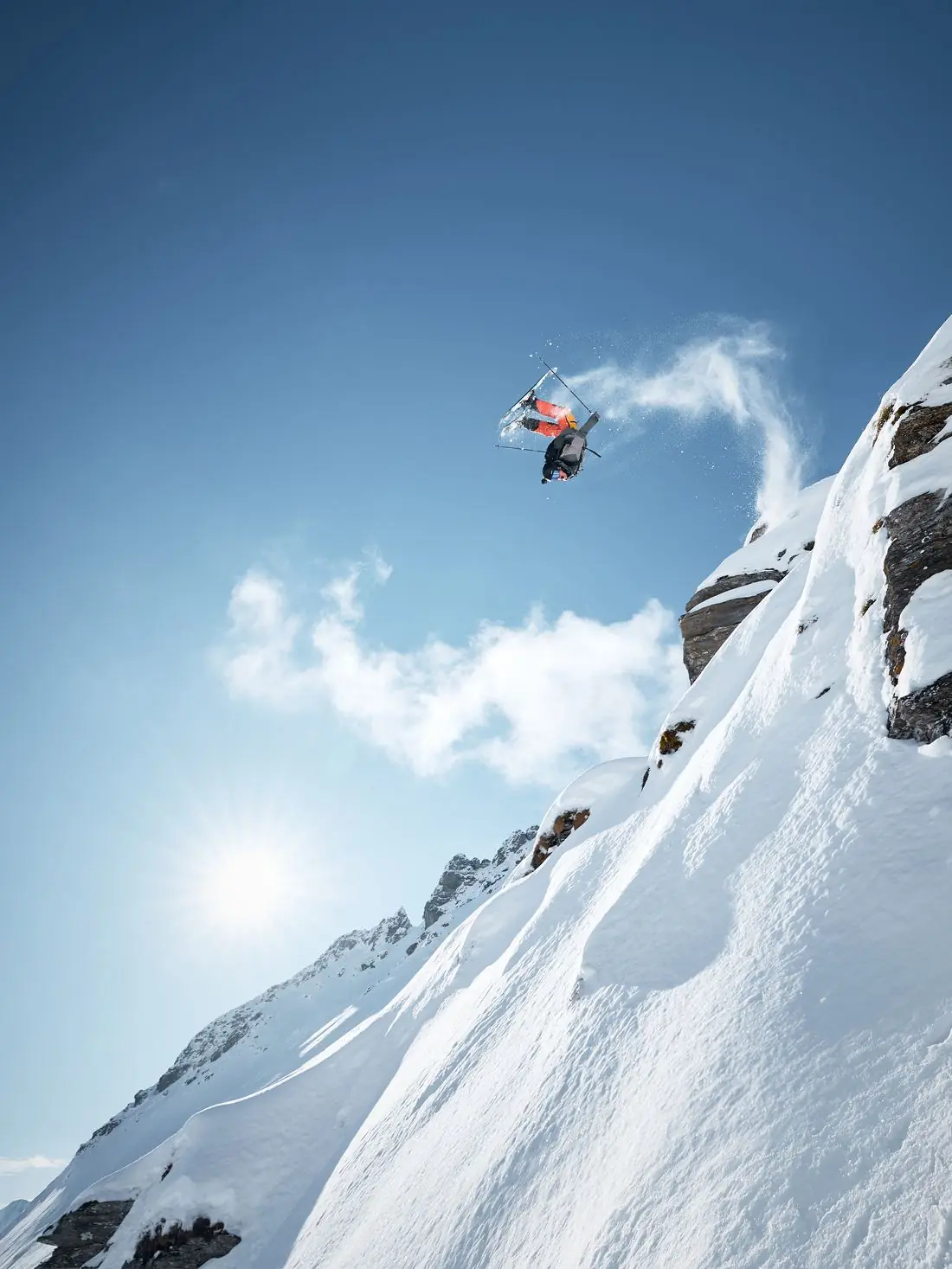 Skifahrer im Sprung vor steiler, verschneiter Felswand – Sportfotografie von Didi Körbler
