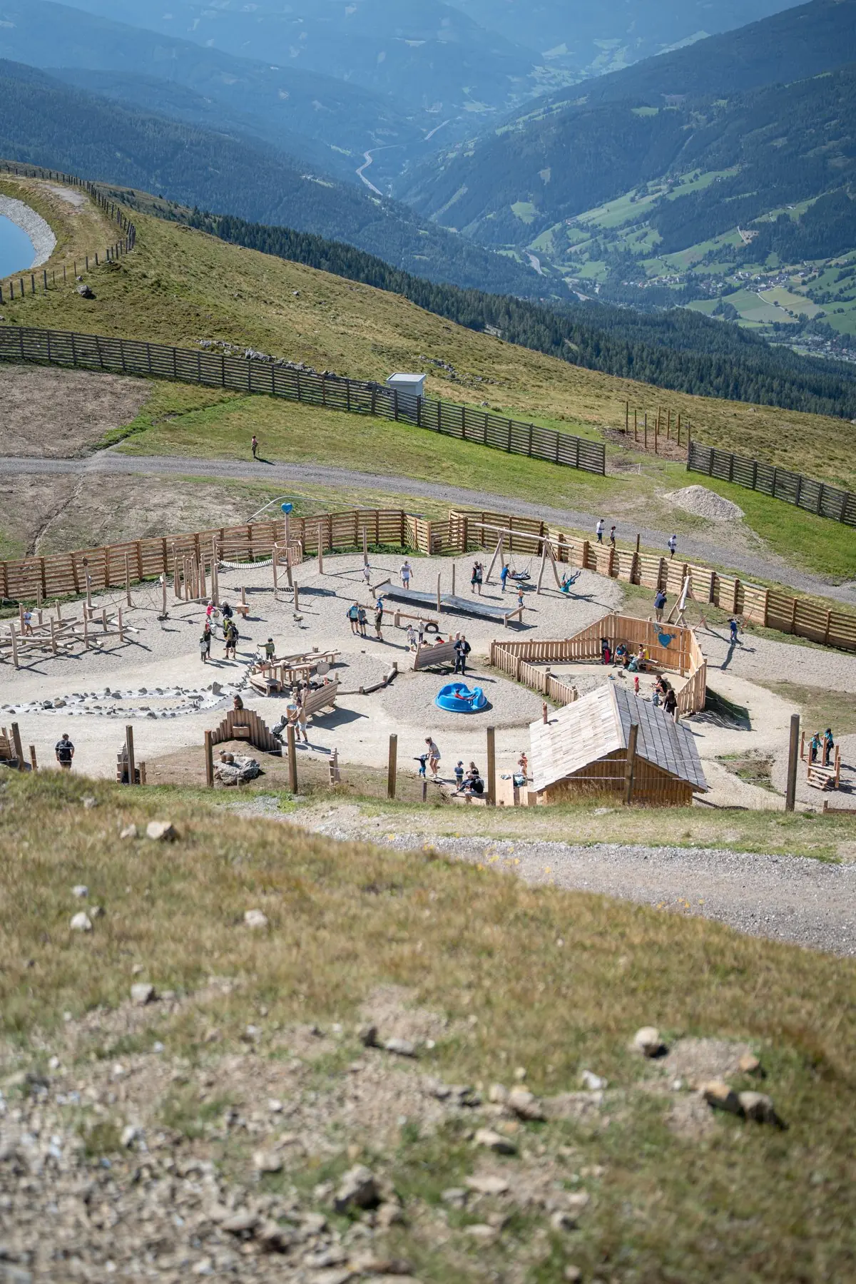 Katschis Almspielplatz von oben mit Speicherteich und Blick ins Tal