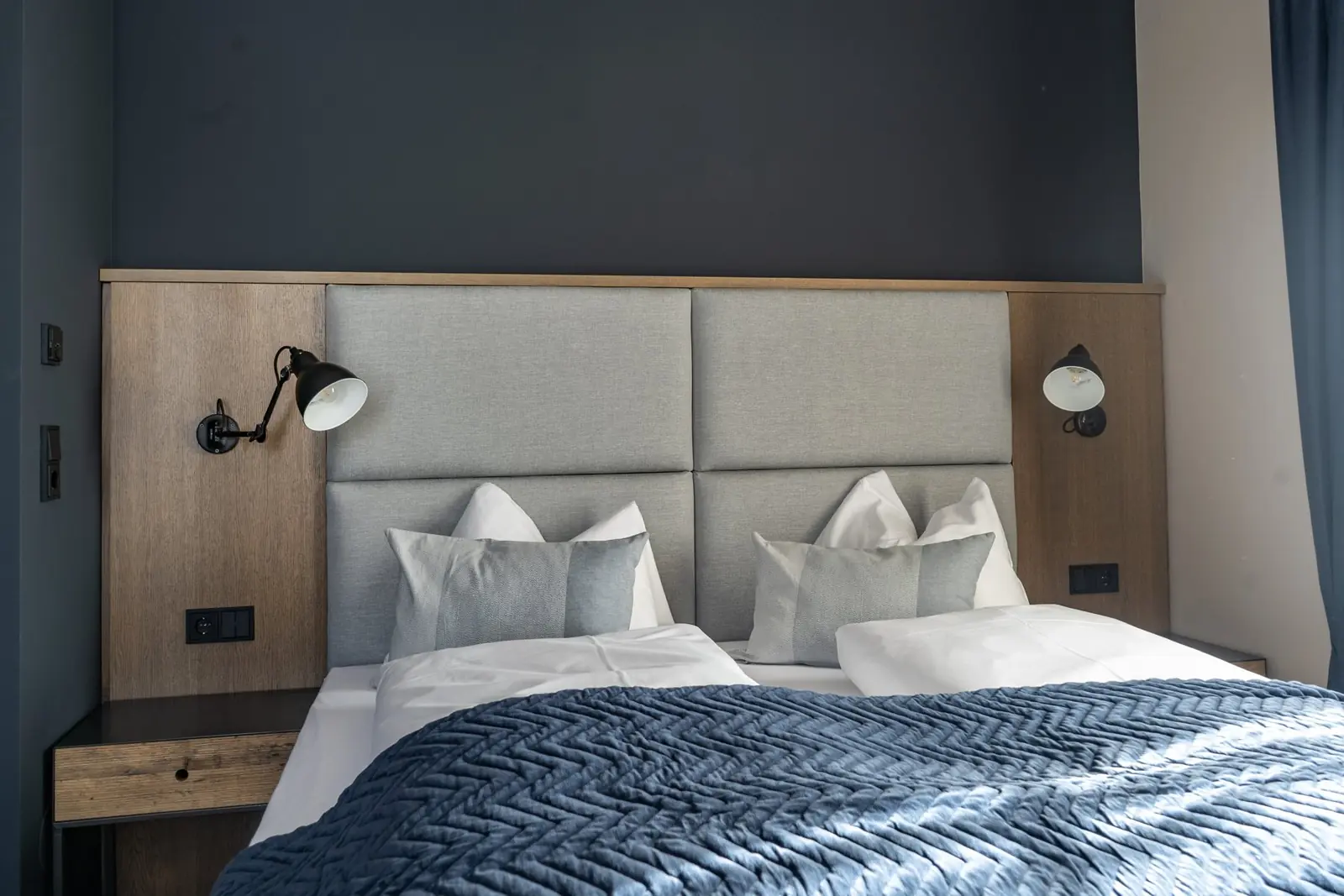 Schlafzimmer im Boutique-Apartment Herbert mit dunkler Wand und Holz