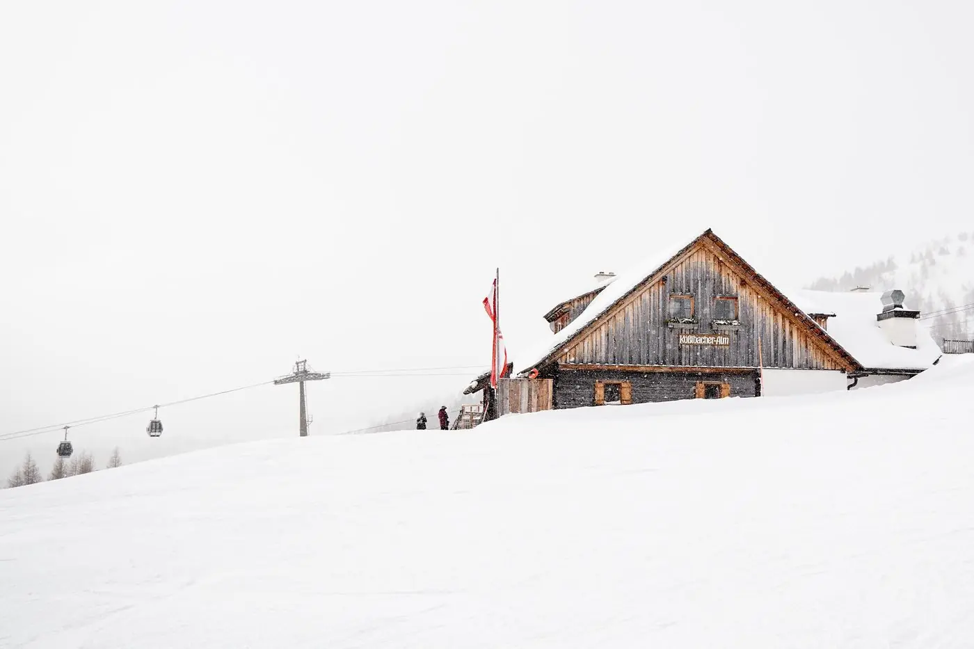 Holzhütte der Kösselbacher Alm im Schnee mit Skilift am Katschberg